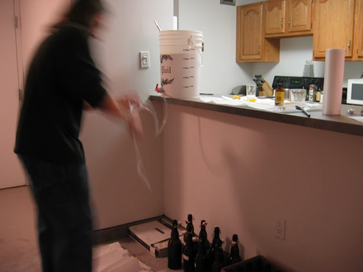 a person in a kitchen with a jug and some bottles