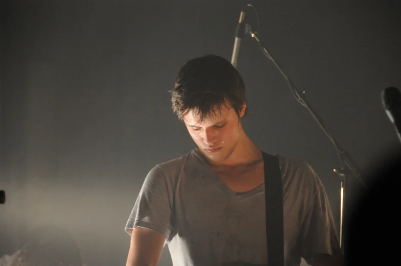 the young man is playing a guitar and looking down