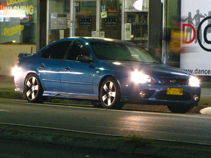 a blue car is sitting at a street corner