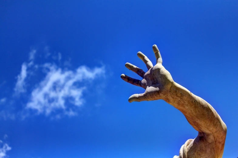 an outstretched hand statue against the blue sky