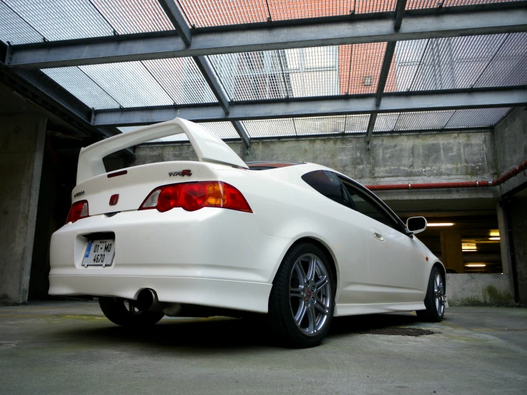 the back view of a white sport car in a parking garage