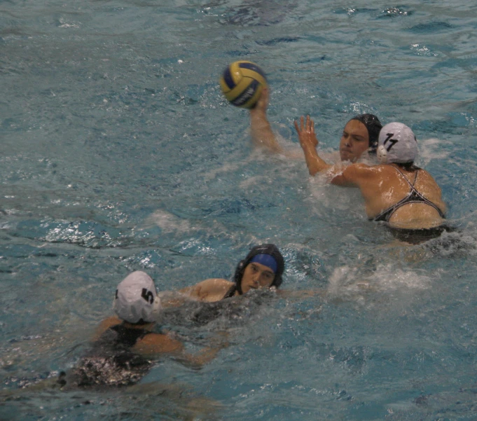 two women play in the water and one is catching a ball
