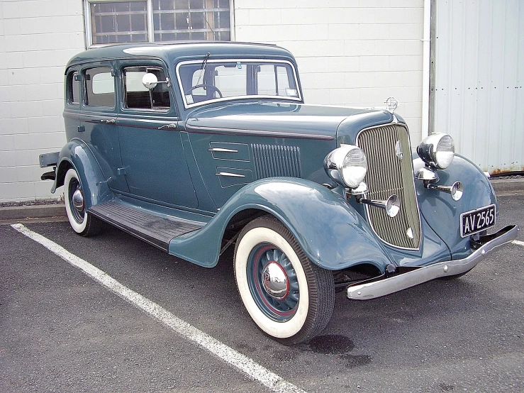 an old antique blue car parked in front of a garage