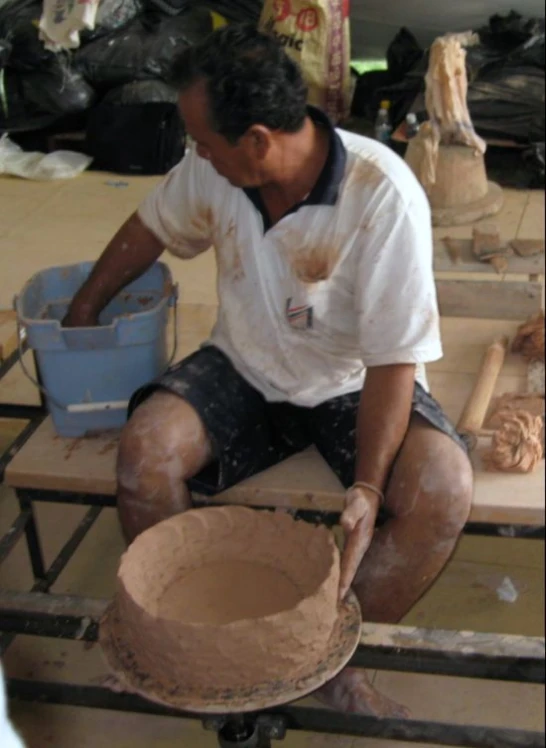 a man is waxing a pot sitting on a stool