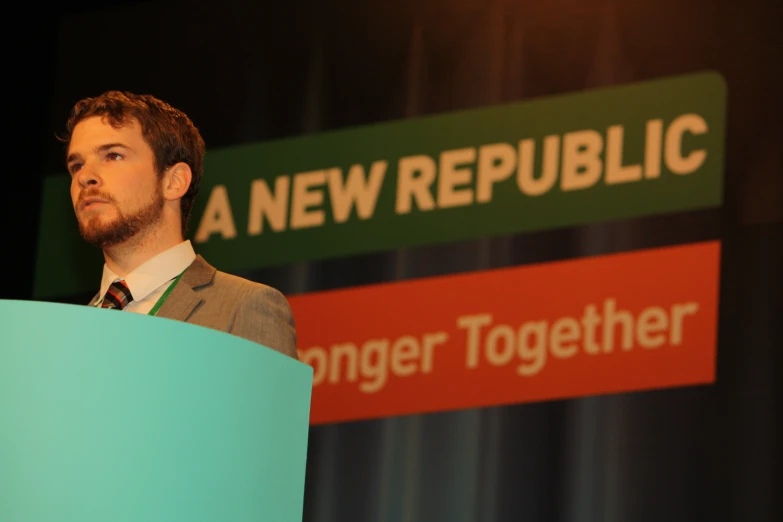 a man standing at a podium in front of a banner