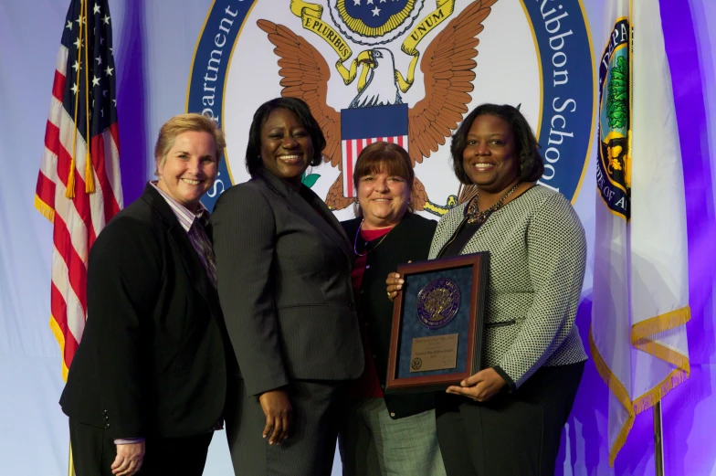 two women and one woman are holding an award