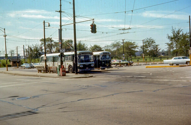 two buses and cars parked at a bus stop