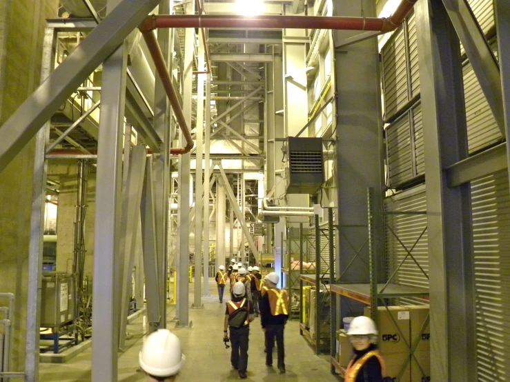 men in safety vests walking in a large industrial building