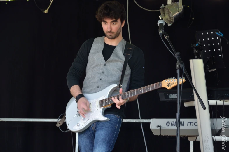 a man sitting on a chair playing an electric guitar