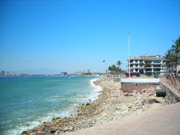 there are many people walking down the sidewalk next to the beach