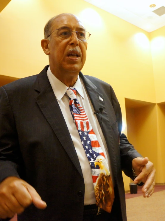 a man in suit with american flag tie talking