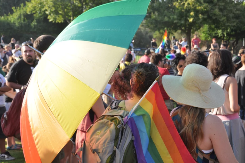 people stand under a colorful umbrella in the crowd