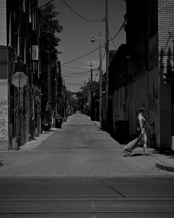 an empty city street, with buildings, and a person sitting on the side of the road