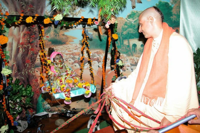 a man sits by a decorated shrine