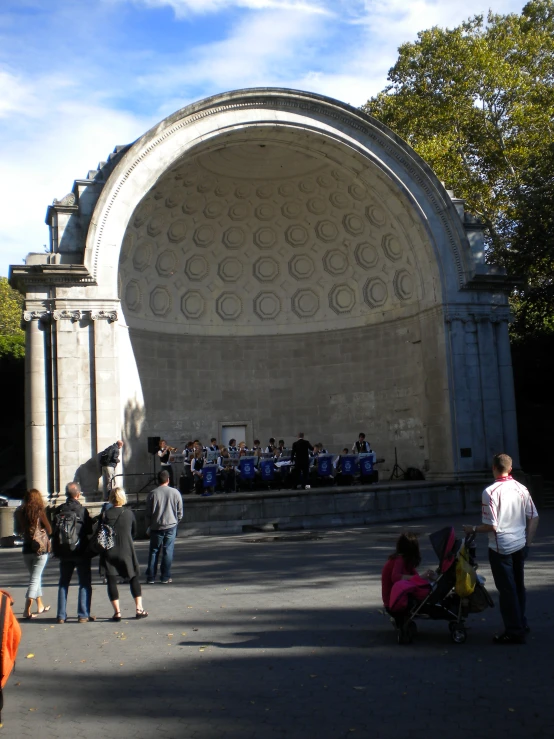 a crowd of people standing around in front of a stone archway