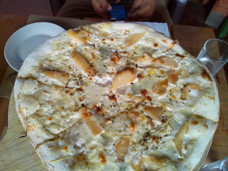 a pizza with different cheese toppings and people around it