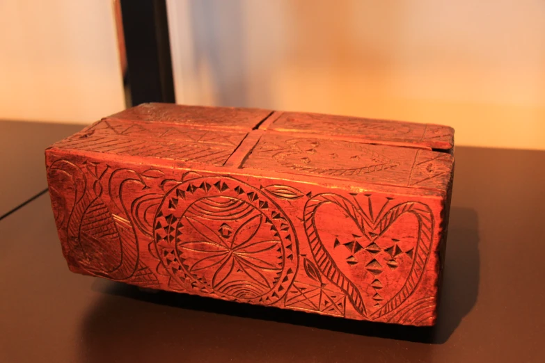 a red wooden box with an ornate design on it