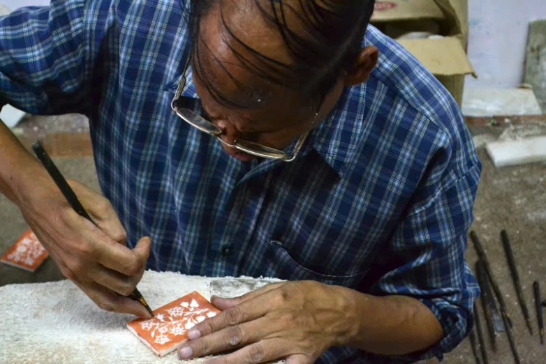 a person in a shirt and glasses working on a small item