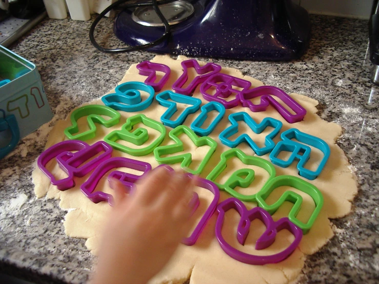 a child's hands are decorating letters with neon colored plastic