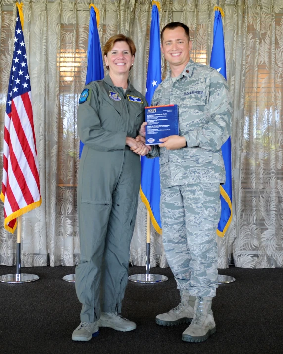 a woman and man in uniform stand together in front of flags