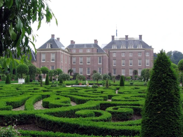 a large building with many trees and bushes in front