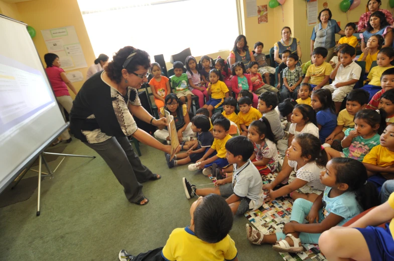 an audience in a school sitting in front of a projector