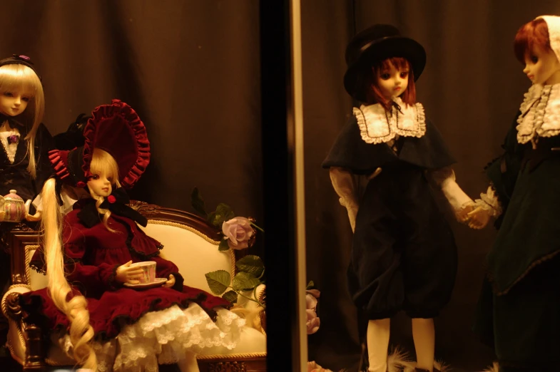 two doll sitting on an old chair and another in the background