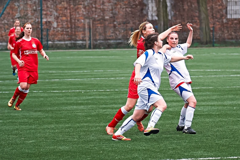 three girls in uniforms playing soccer on the field