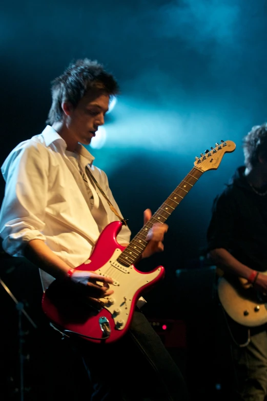 two men standing next to each other with guitars