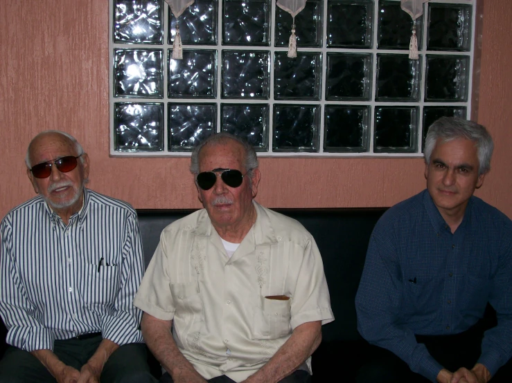 three old men sitting on top of a black couch