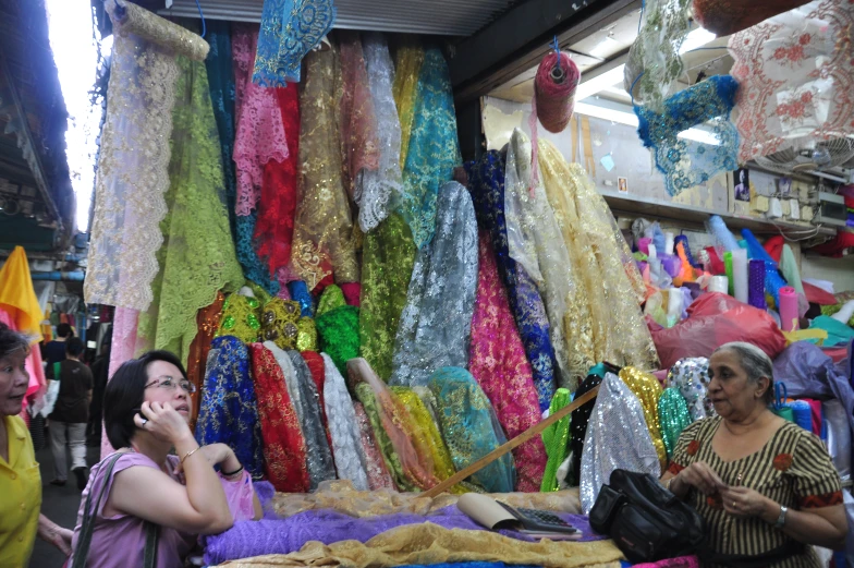 several women standing around in front of various colorful clothing