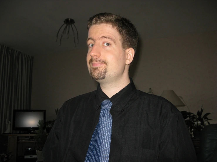 a man in black shirt and blue tie posing for the camera