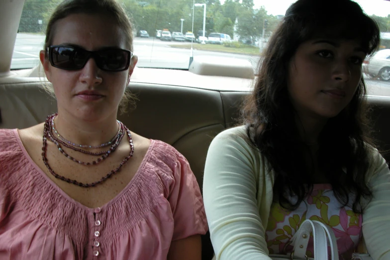 two woman wearing glasses in the back of a car