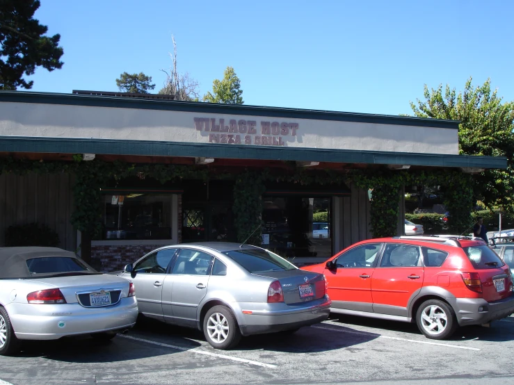 two vehicles parked outside a pizzeria that is empty