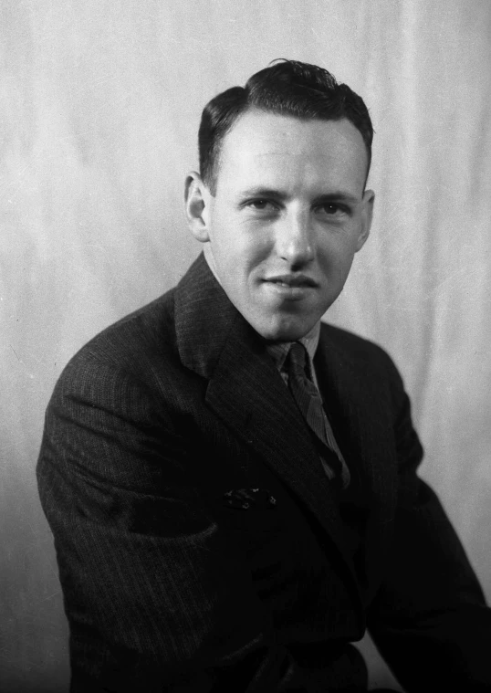 man wearing a black and white suit and tie with dark hair