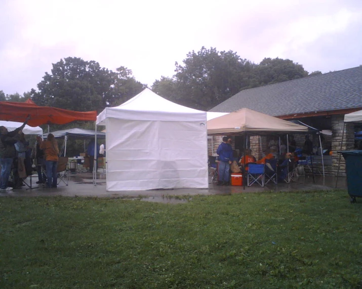 people are gathered around a tent outside in a field