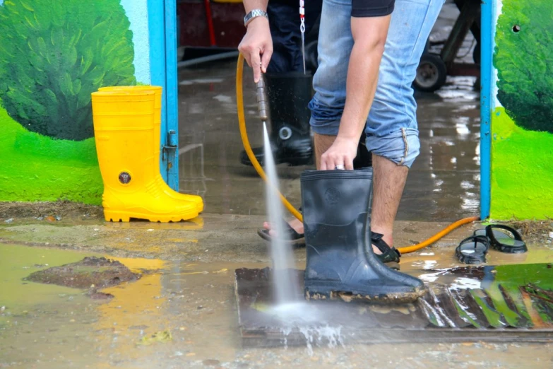 a man using a fire hydrant to wash a driveway