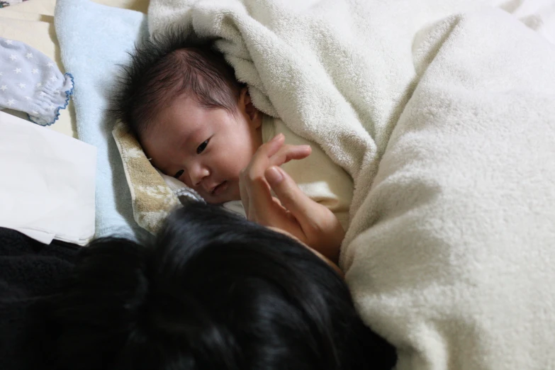 a baby smiles while lying in its owner's arms