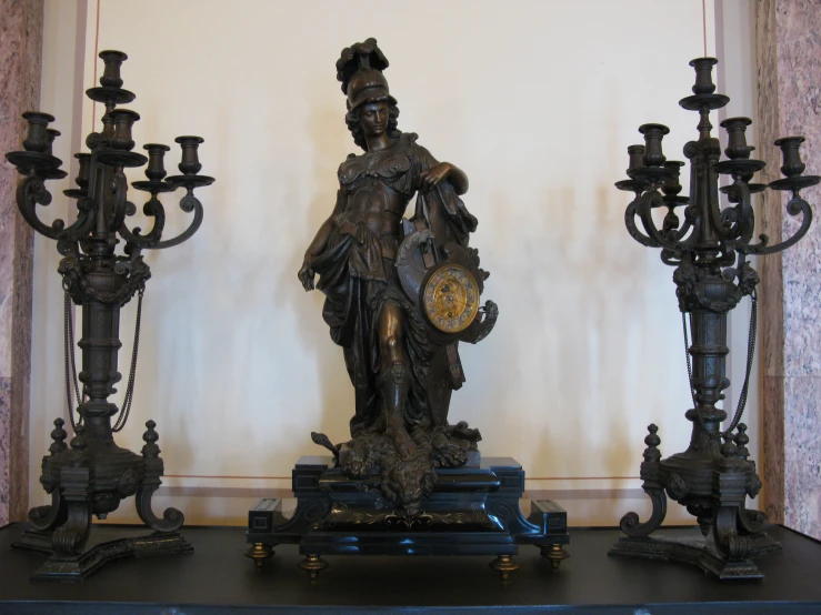 three antique candela with a statue on top of them