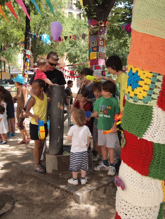 a group of children and adults gathered around a pole