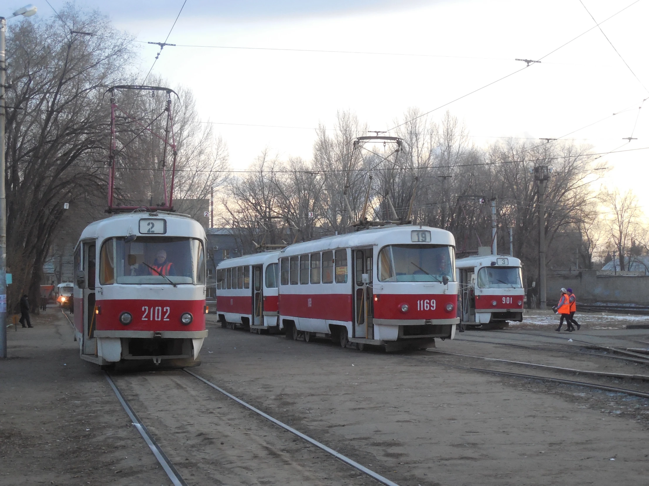 people walk in a station next to two trains on tracks