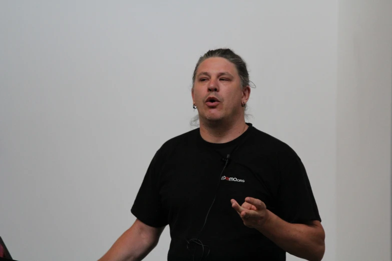 man wearing black shirt and talking while standing with camera