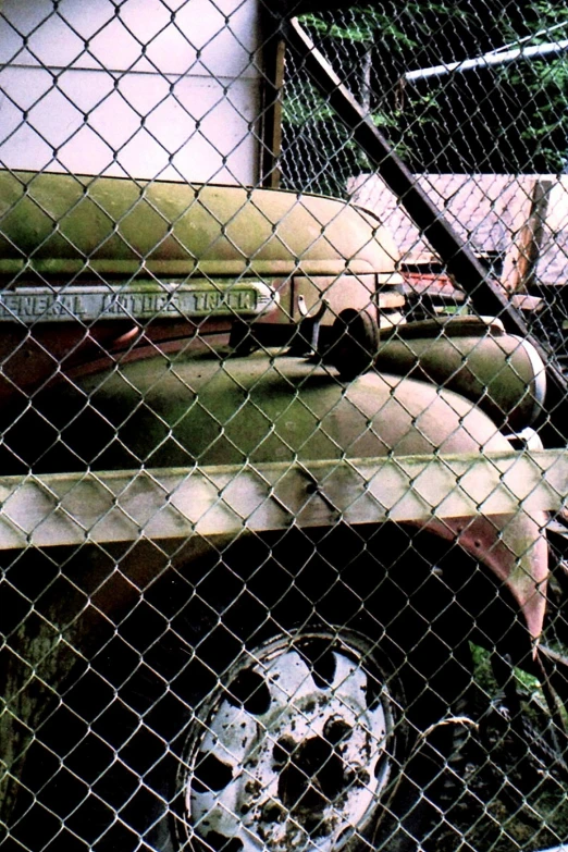 an old vehicle behind a fence with an older logo