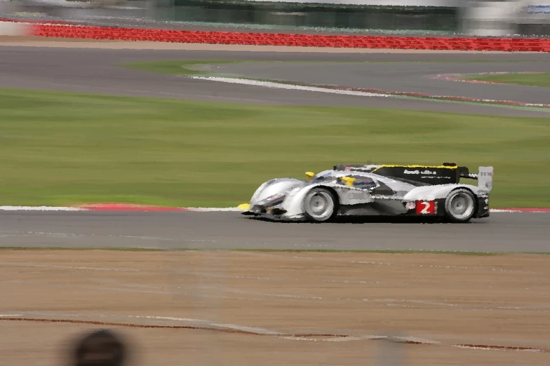 a silver race car driving around a corner