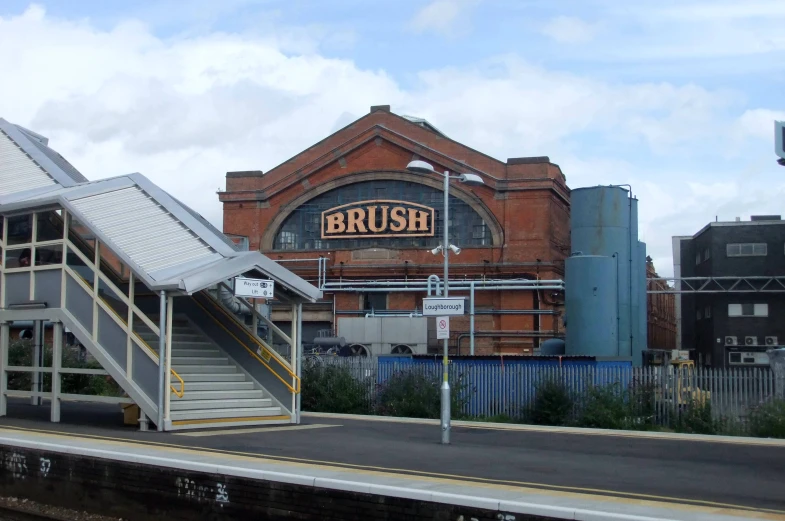 a train is passing by a building with a sign that reads brush