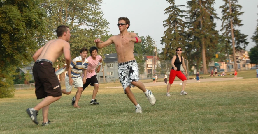 a group of men are playing with frisbee in a park