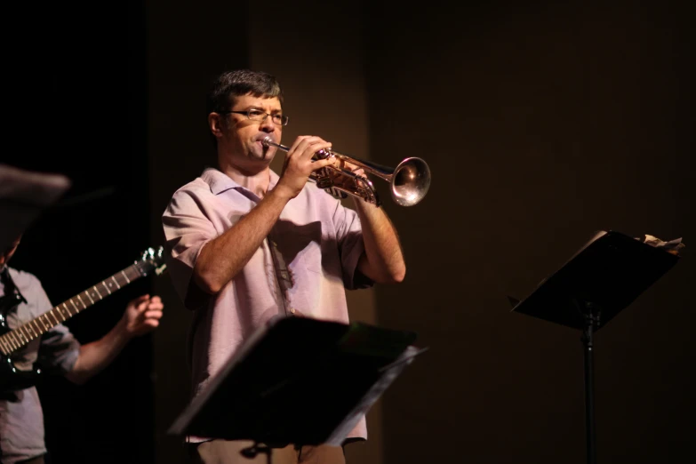 a man in pink shirt playing trumpet with orchestra instruments