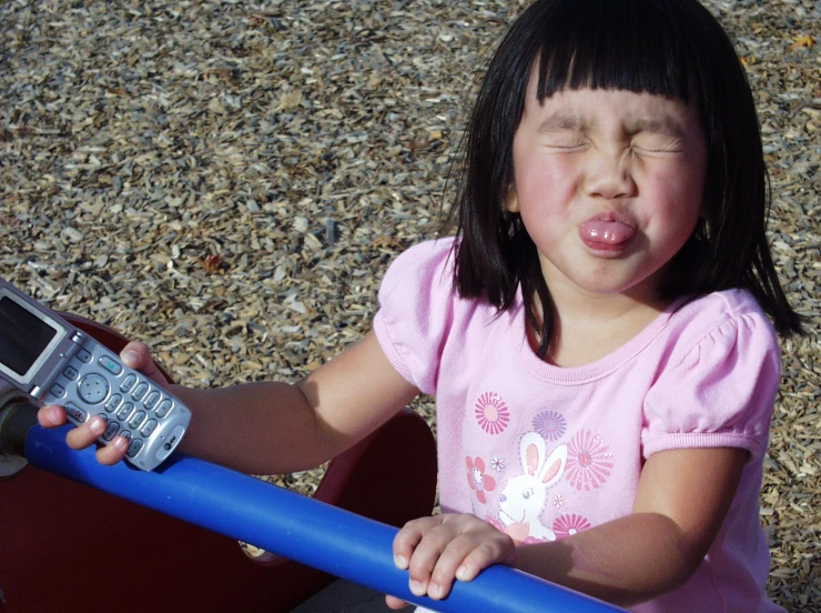 a small child on a toy truck with a phone