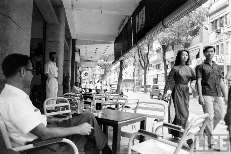 two young people walking on a sidewalk near an outdoor cafe