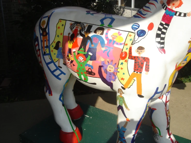 a cow with different pictures on its face sitting outside